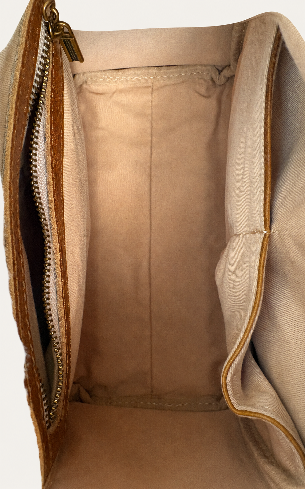 Close-up of the interior of a beige canvas or nylon bag, showing the lining, zipper track, and stitched edges.
