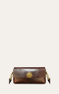A brown leather crossbody bag with a textured finish, a gold sunburst button clasp, and gold-tone hardware, shown against a light beige background.