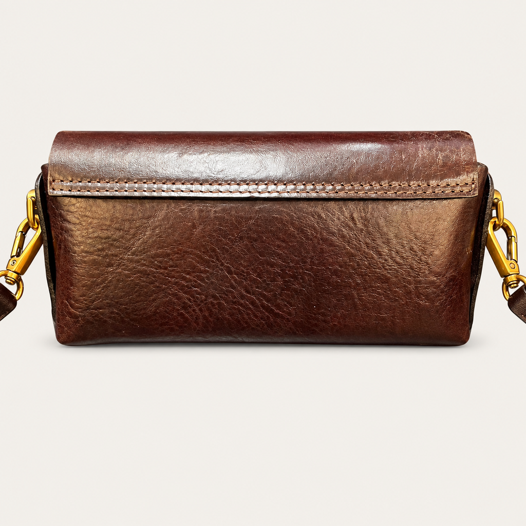 A brown leather clutch bag with gold-tone hardware and a matching leather strap, shown against a light off-white background.