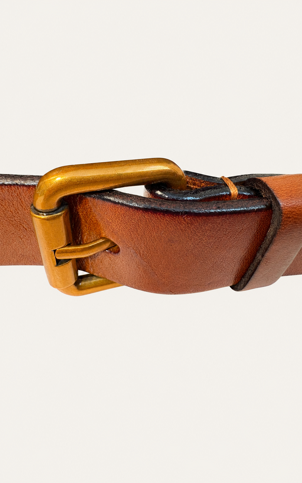 A close-up of a brown leather belt with a gold-toned metal buckle, set against a plain off-white background.