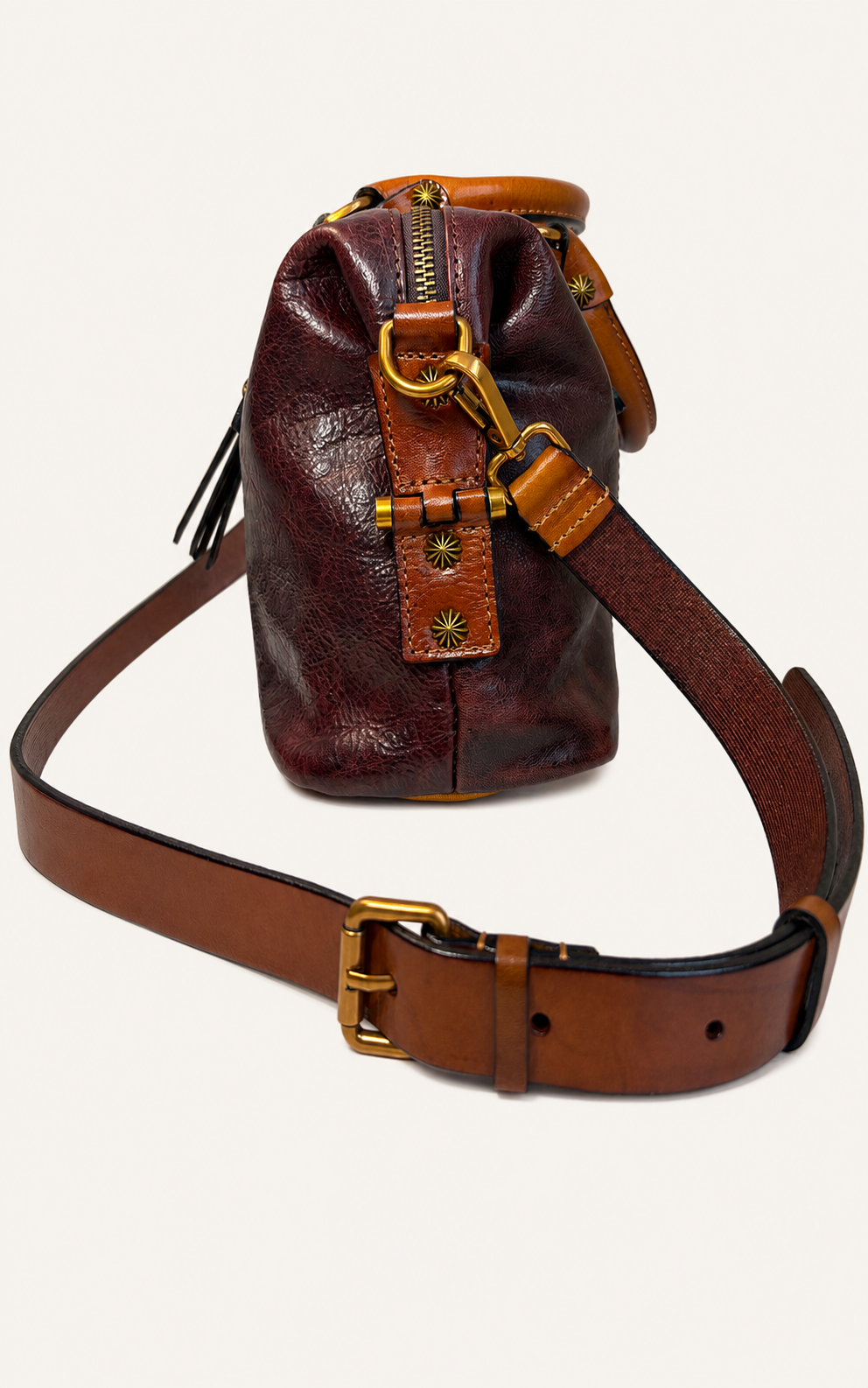 A small leather bucket bag in dark reddish-brown with tan leather trim and a long adjustable brown shoulder strap, shown on a plain light background.
