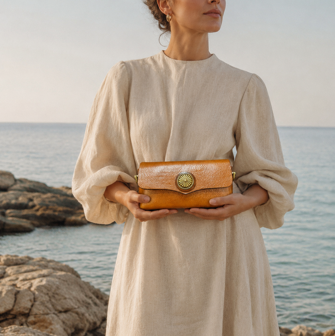 Woman holding a brown leather clutch by the ocean