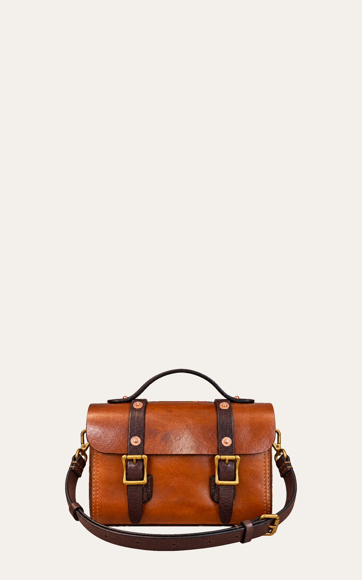 A brown leather satchel bag with dark brown straps and gold-tone buckles, shown against a plain light beige background.