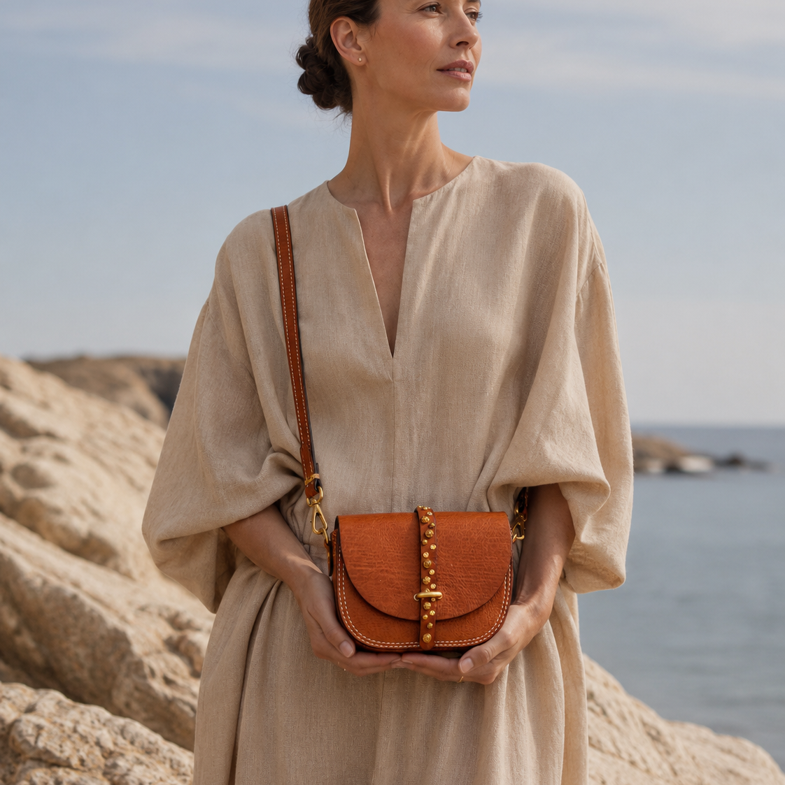 Woman holding a brown leather handbag by the ocean